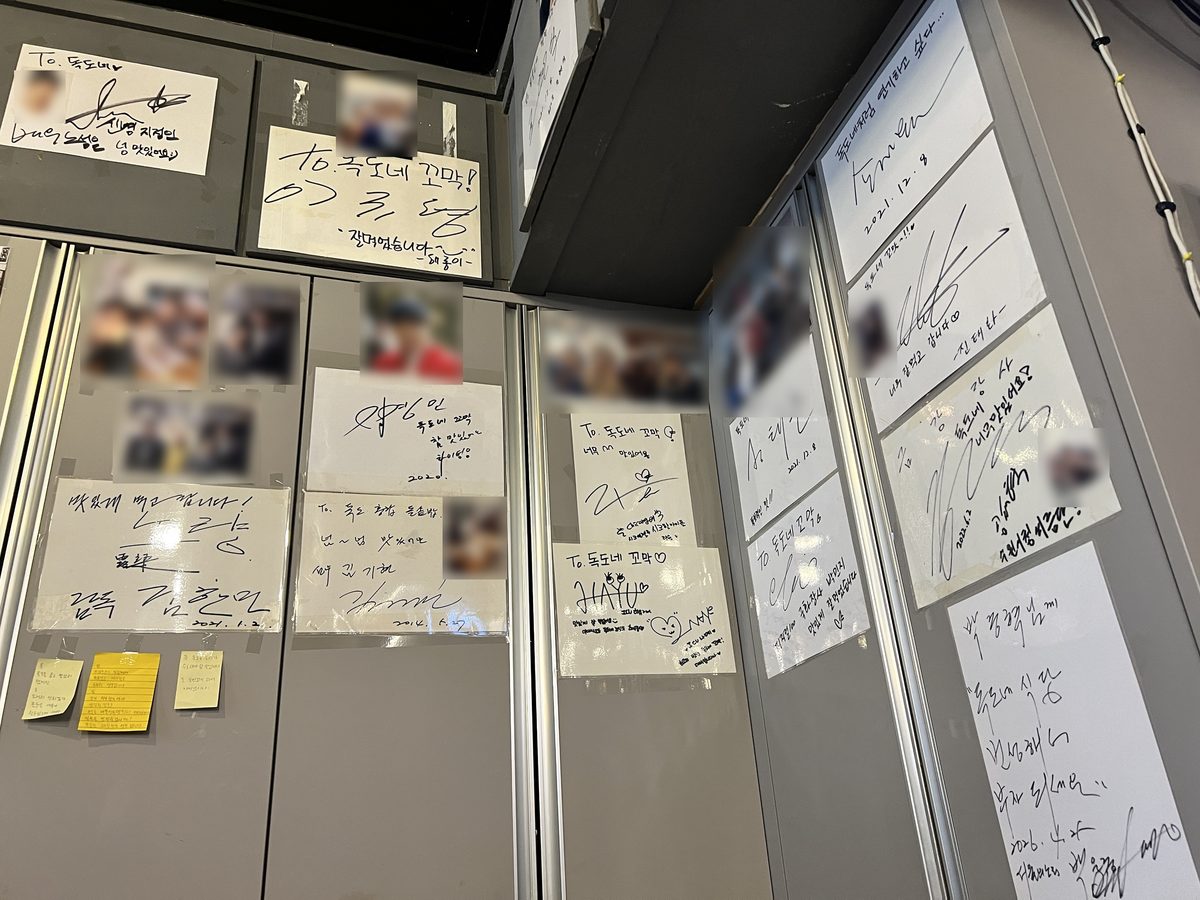 독도네 본점 안쪽 벽에 붙은 사인 카드와 사진 — 사진 속 얼굴은 흐림 처리했다 (2026년 9월 12일 직접 촬영)