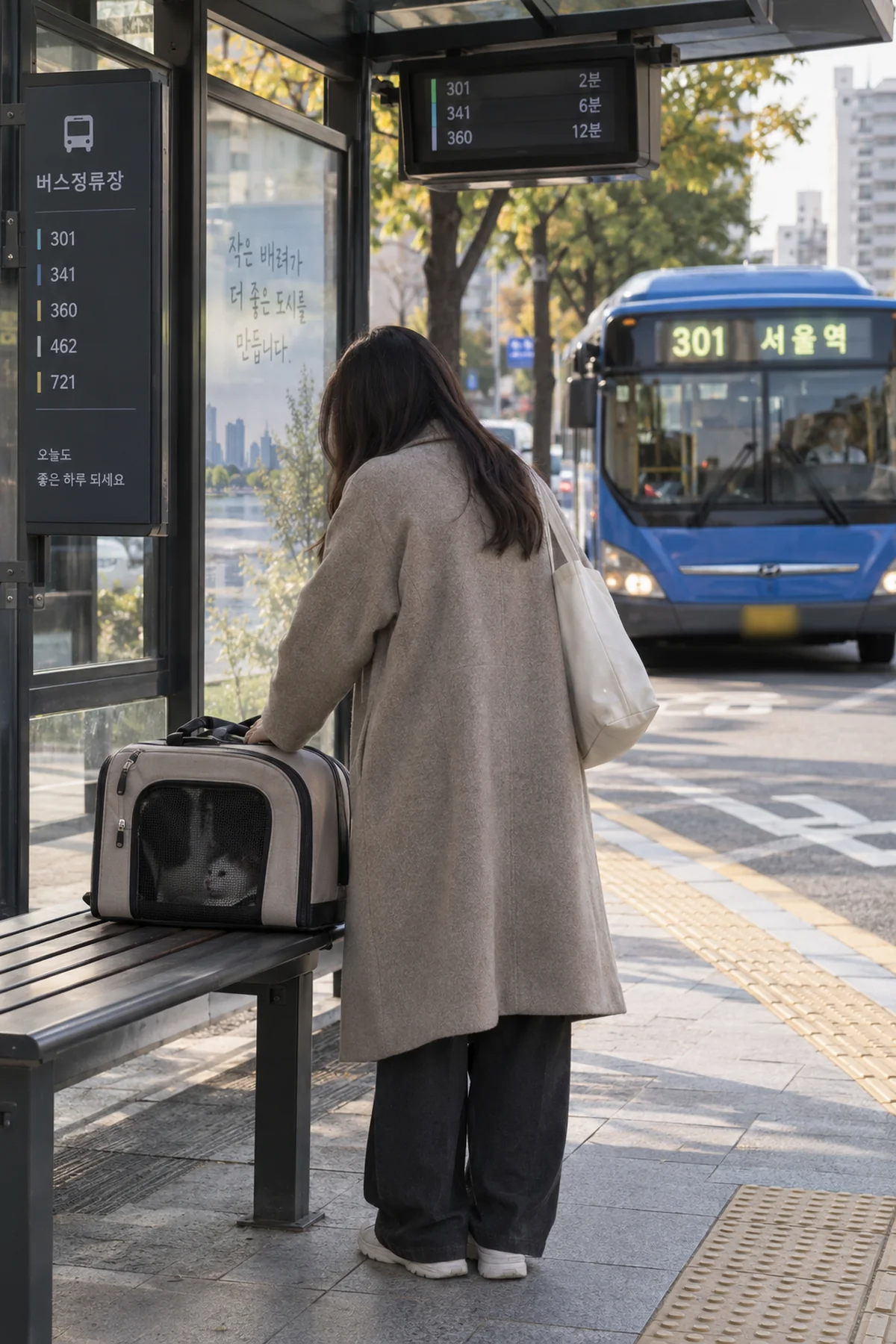 보호자가 정류장에서 이동장 속 반려동물 상태를 살피는 장면